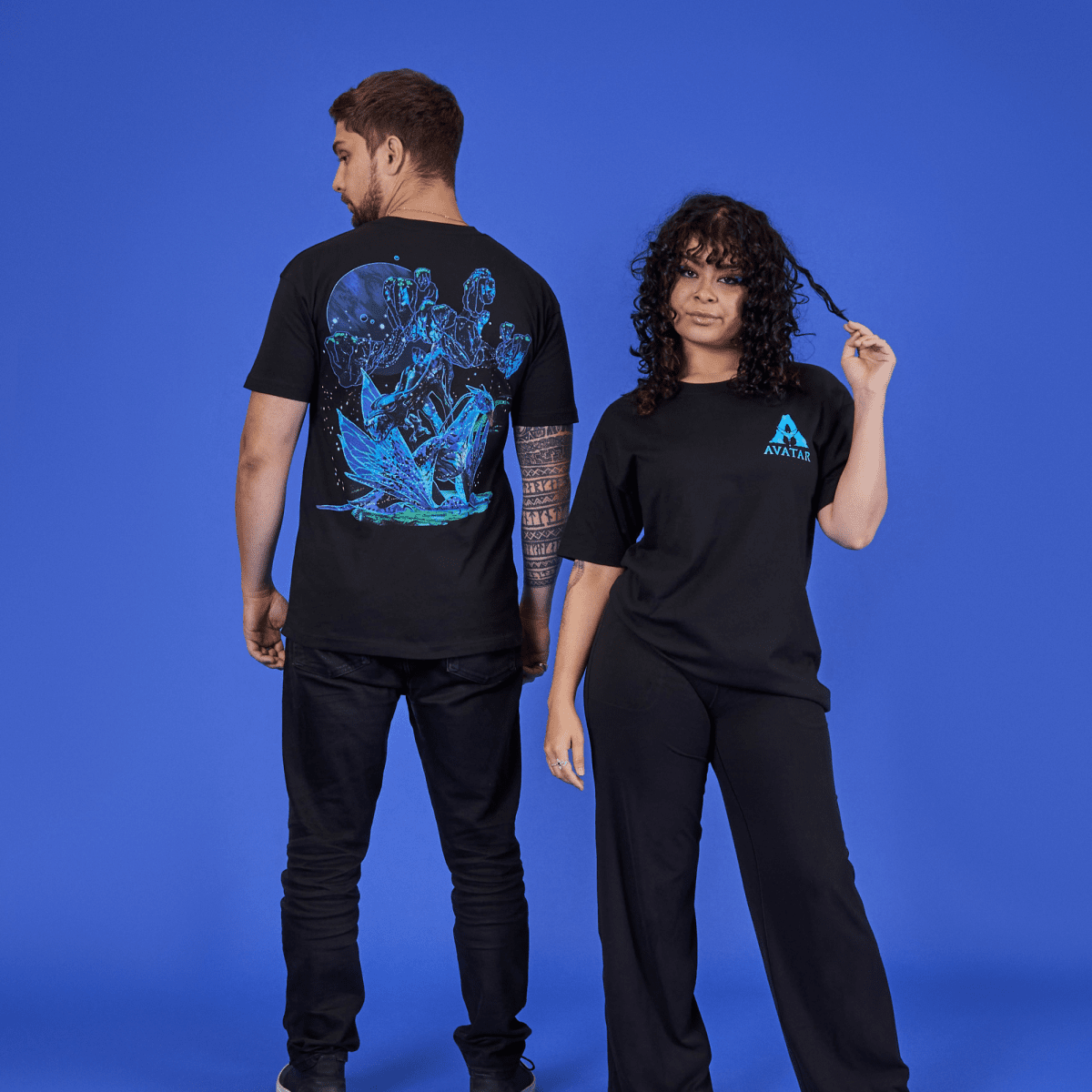 Two people wearing black t-shirts with colorful designs on a blue background