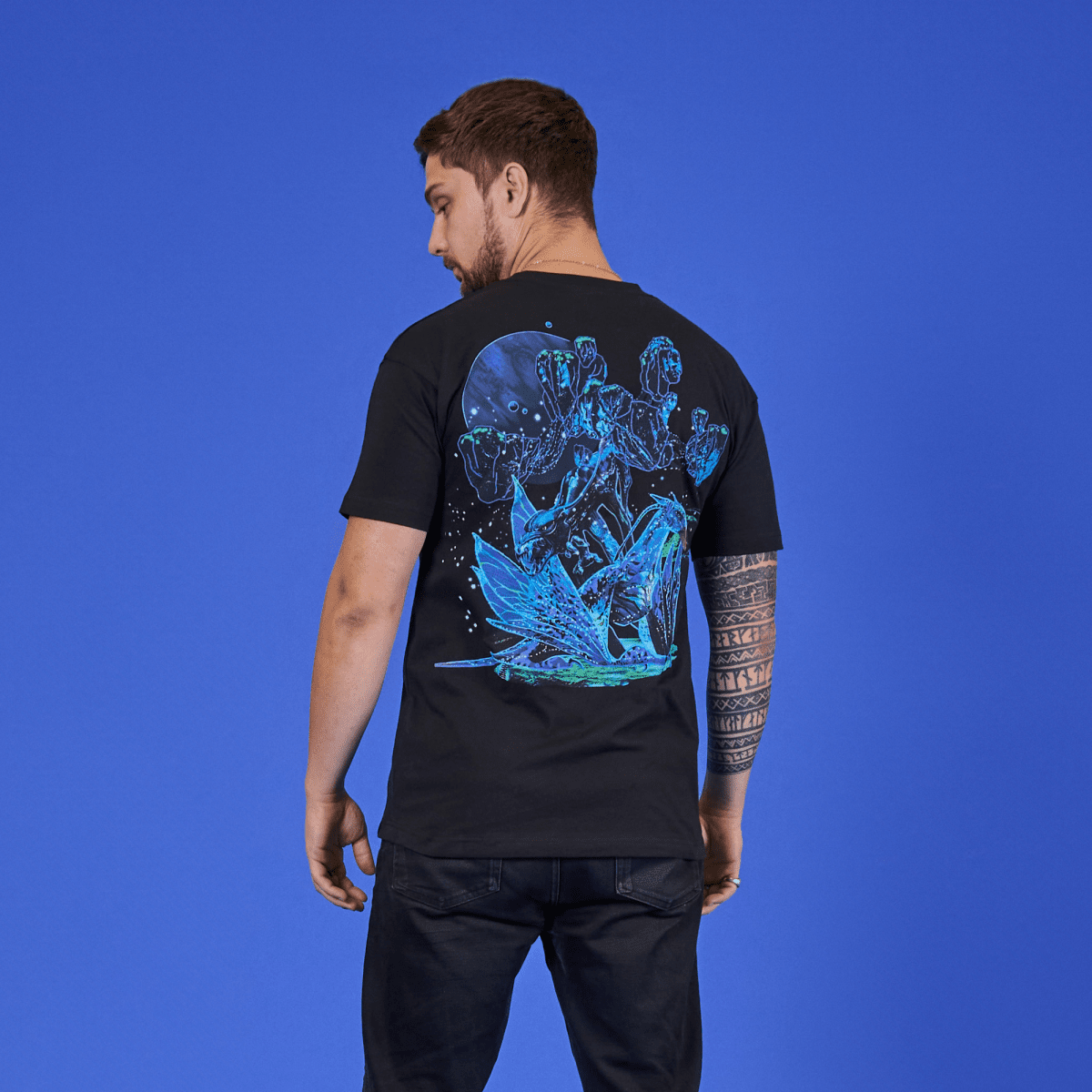 Man wearing a black t-shirt with a blue graphic design on the back against a blue background