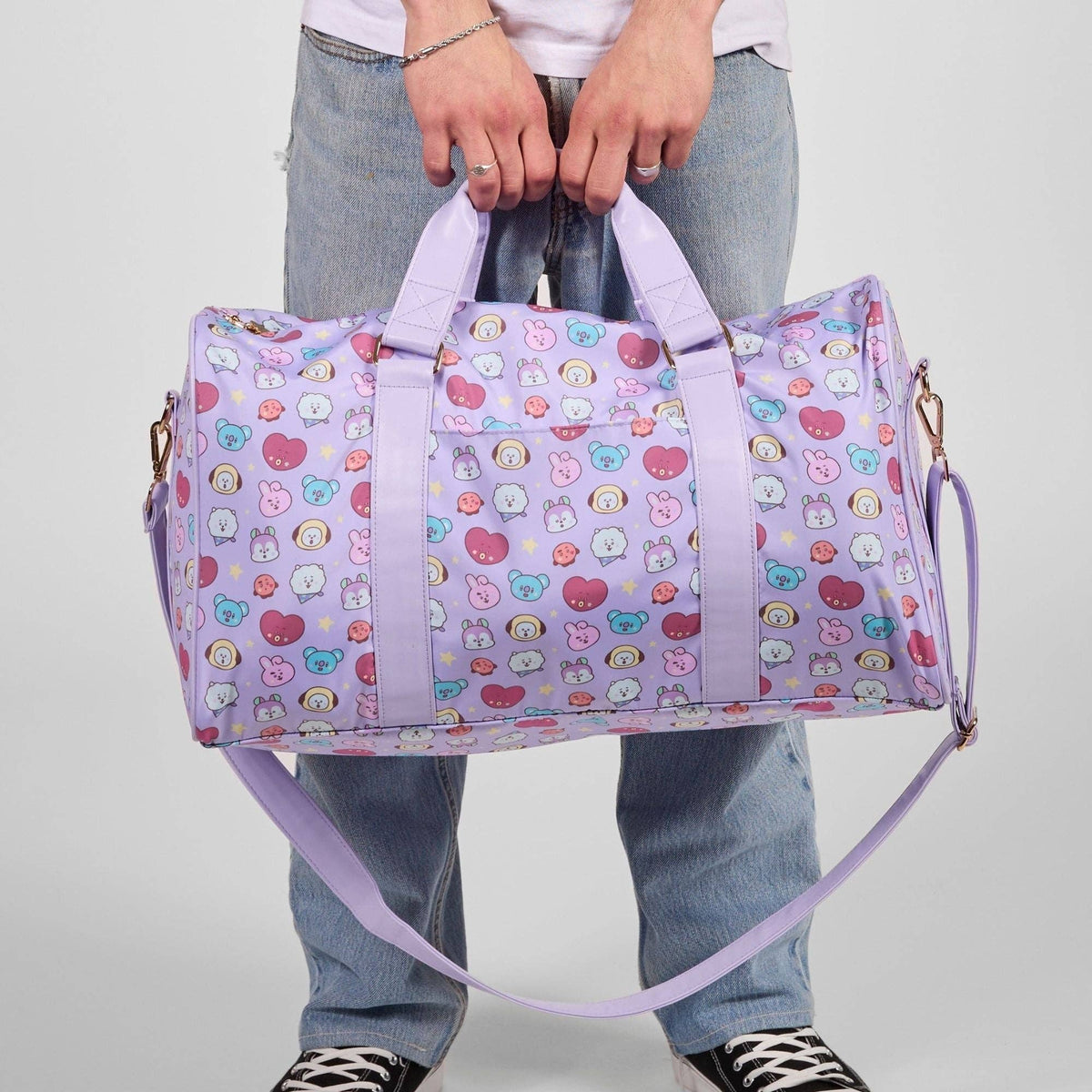 Person holding a colorful patterned duffel bag against a plain background