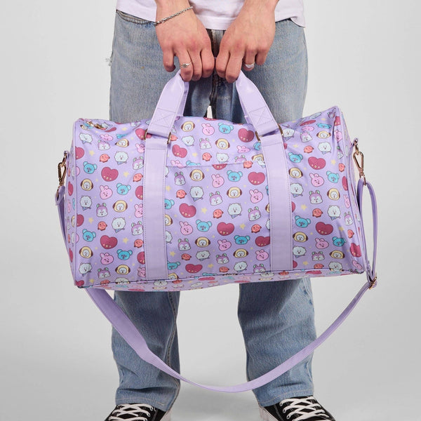Person holding a colorful patterned duffel bag against a plain background