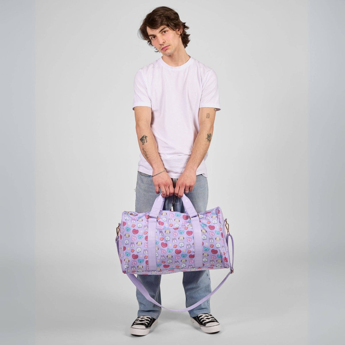 Person holding a patterned duffel bag against a plain background