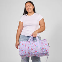 Person holding a purple duffel bag with cartoon character pattern against a plain background