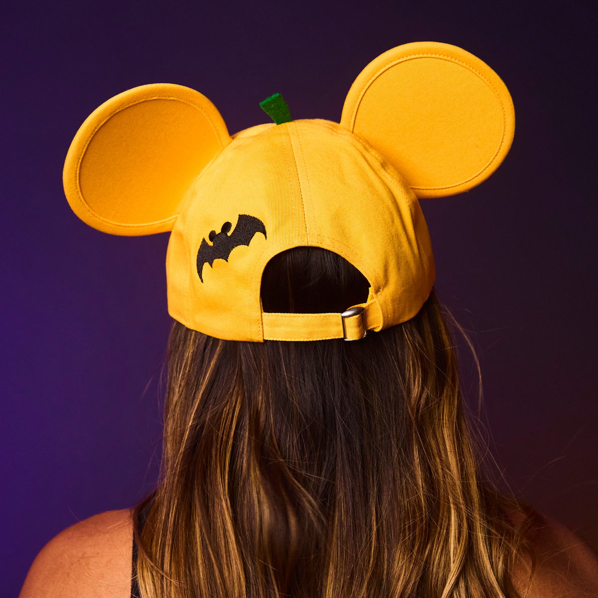 Orange cap with bat design and ears on a purple background