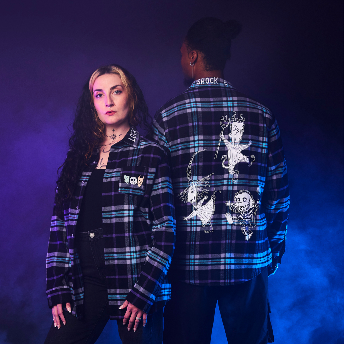 Two people wearing plaid shirts with graphic designs on a gradient purple to blue background