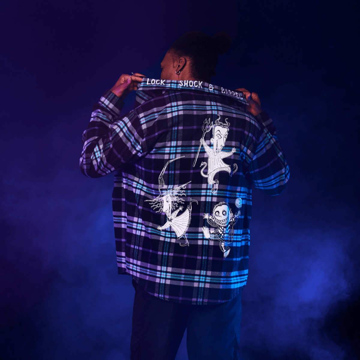 Person wearing a plaid shirt with graphic designs on a dark background
