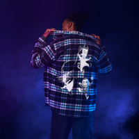 Person wearing a plaid shirt with graphic designs on a dark background