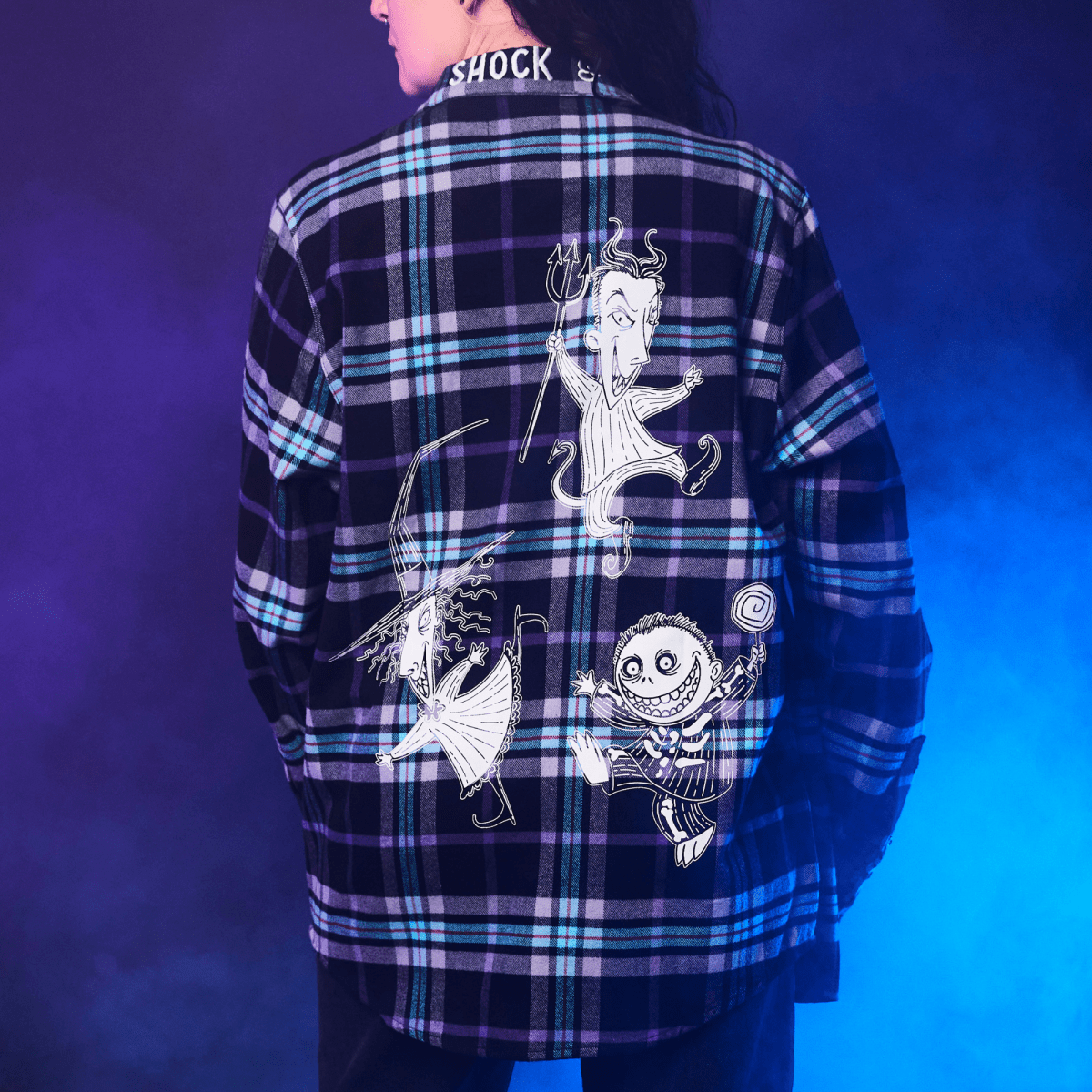 Person wearing a plaid shirt with graphic designs on the back against a blue gradient background