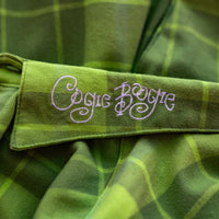 Close-up of a green plaid fabric with 'Oogie Boogie' embroidery.