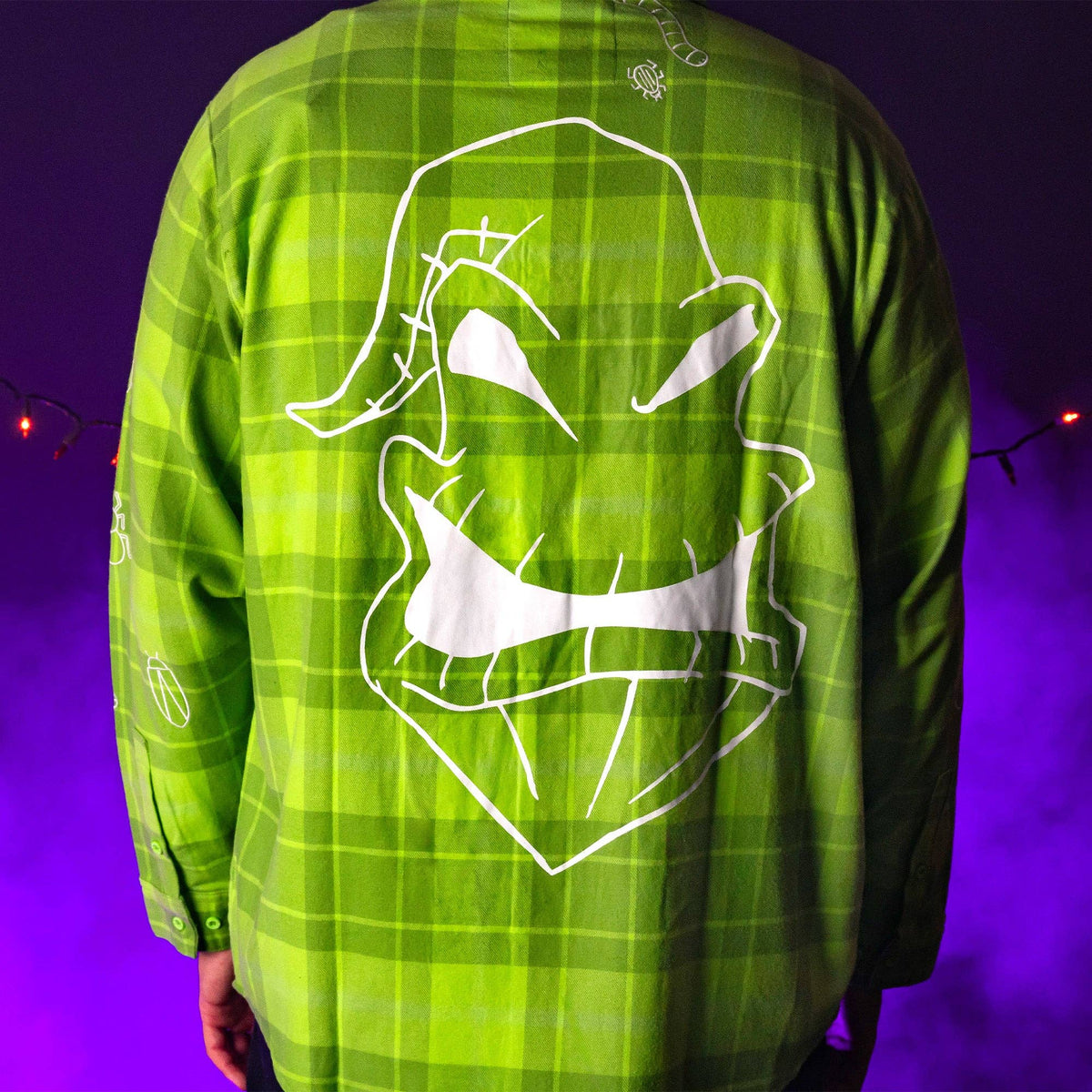 Green plaid shirt with white graphic design on a purple background