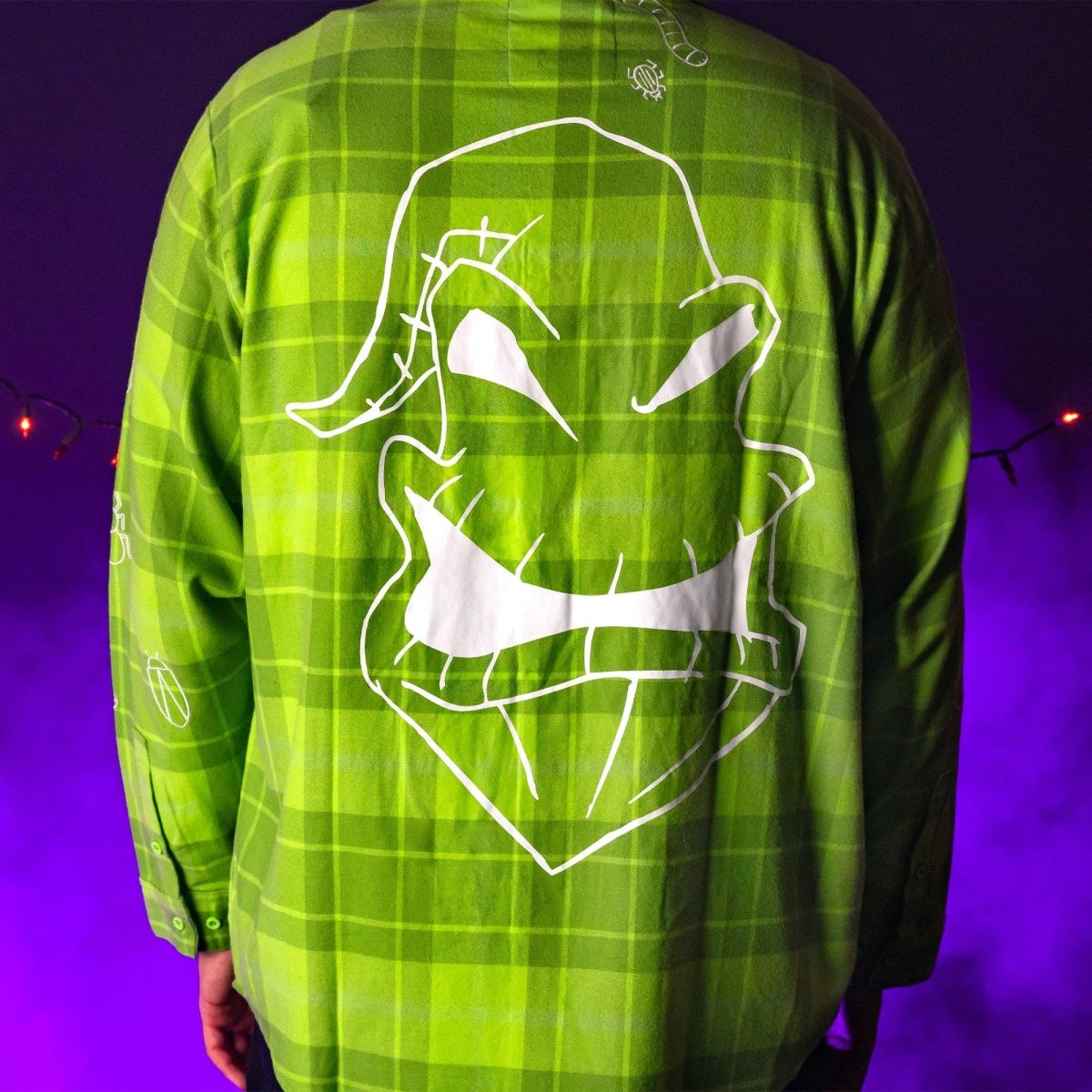 Green plaid shirt with white graphic design on a purple background