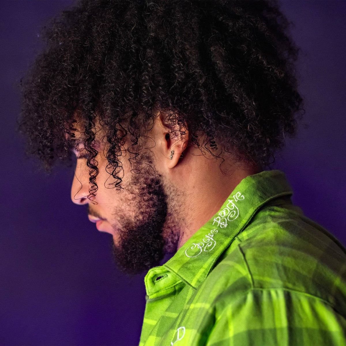 Man wearing a green shirt with a purple background