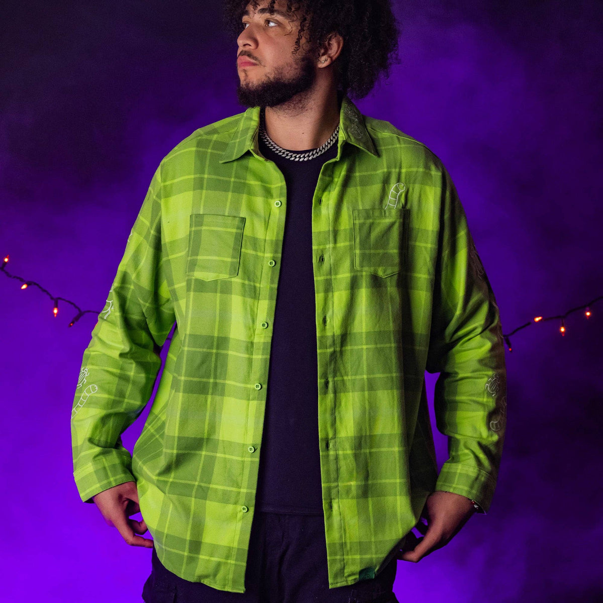 Person wearing a green plaid shirt against a purple background with string lights.