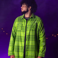 Person wearing a green plaid shirt against a purple background with string lights.