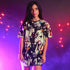 Woman wearing a colorful dress with graphic design against a purple background with string lights.