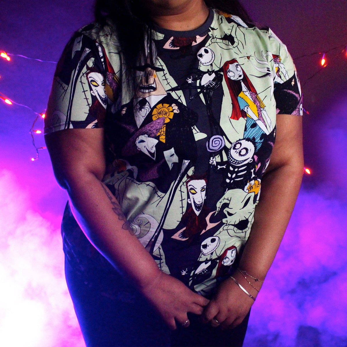 Person wearing a shirt with a colorful character pattern against a purple and pink background.