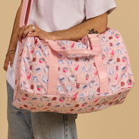 Person holding a Cakeworthy Harry Potter Birthday Duffle Bag against a beige background