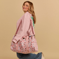 Woman holding a pink Cakeworthy Harry Potter Birthday Duffle Bag against a beige background