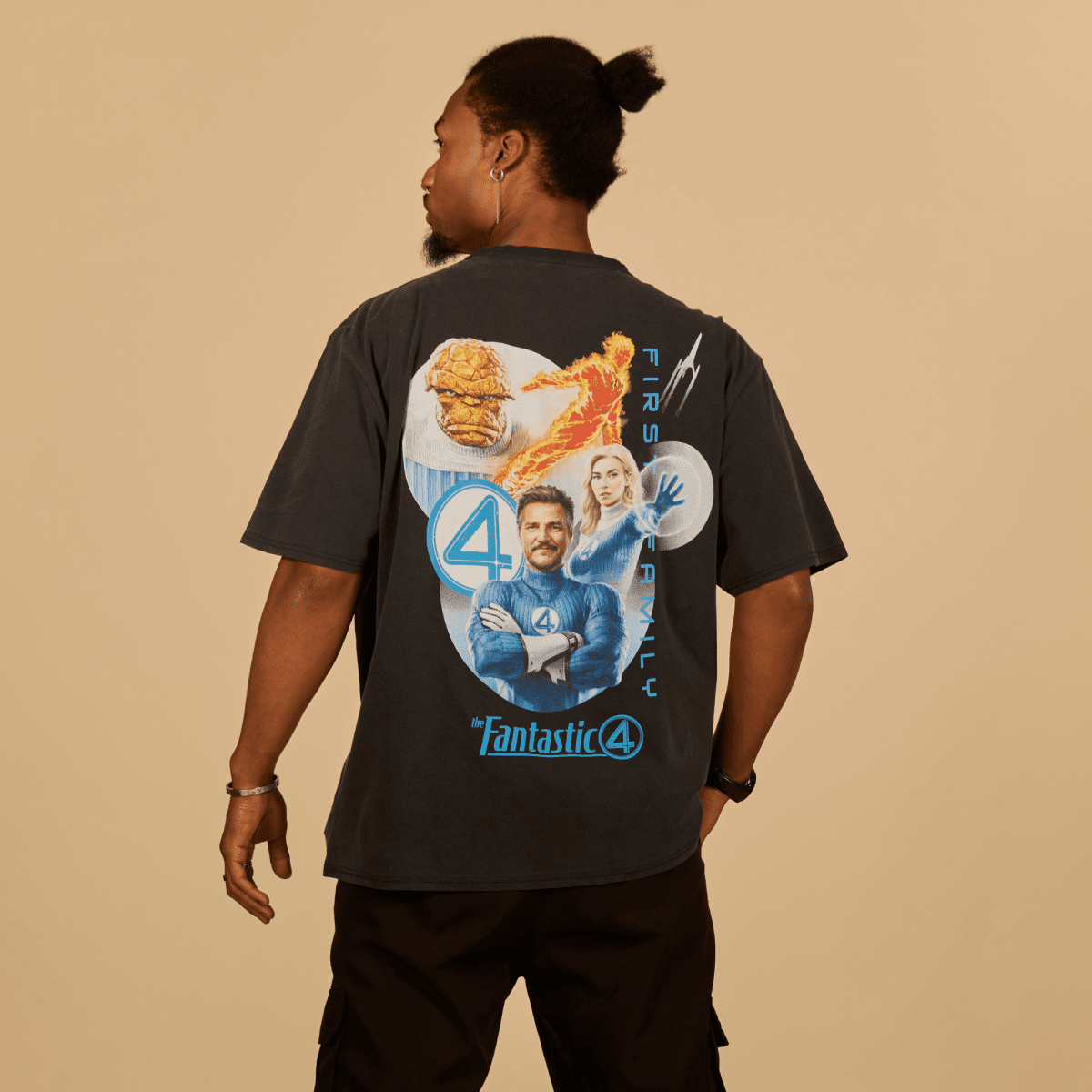Person wearing a black t-shirt with 'Fantastic 4' graphic design on the back against a beige background