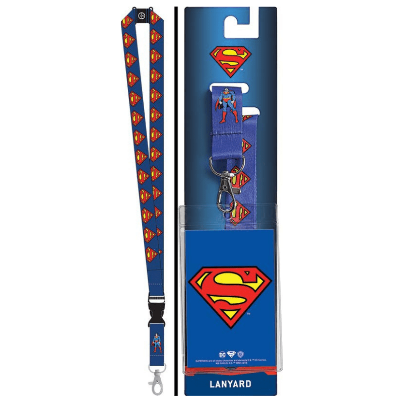 A Superman-themed lanyard shown next to its retail packaging. The lanyard is blue with a repeating pattern of the red and yellow Superman logo, featuring a black adjustable strap and a silver metal clasp.