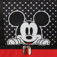 Black bag with white polka dots and a cartoon character peeking out, featuring a red zipper.