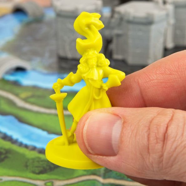 Yellow figurine held by a hand with a blurred game board in the background