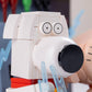 Close-up of a toy camera with a white body, black lens, and red base.