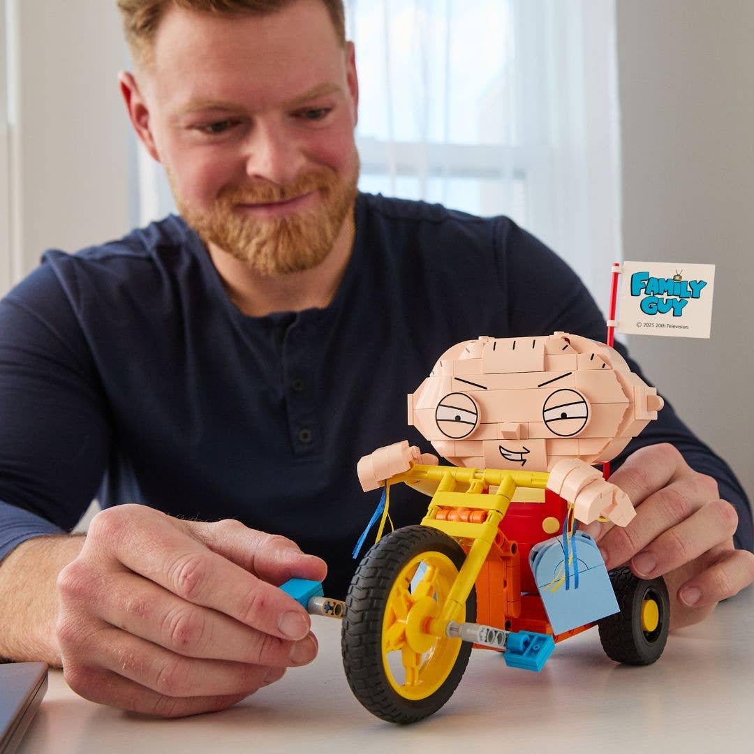Man holding a toy figure of Stewie Griffin from Family Guy on a bike