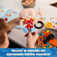 Person holding a small toy figure with building blocks and components on a table.