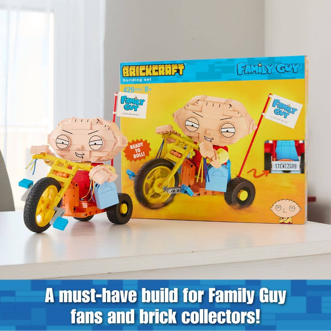 Toy figure of Stewie Griffin on a tricycle with Family Guy packaging in the background.