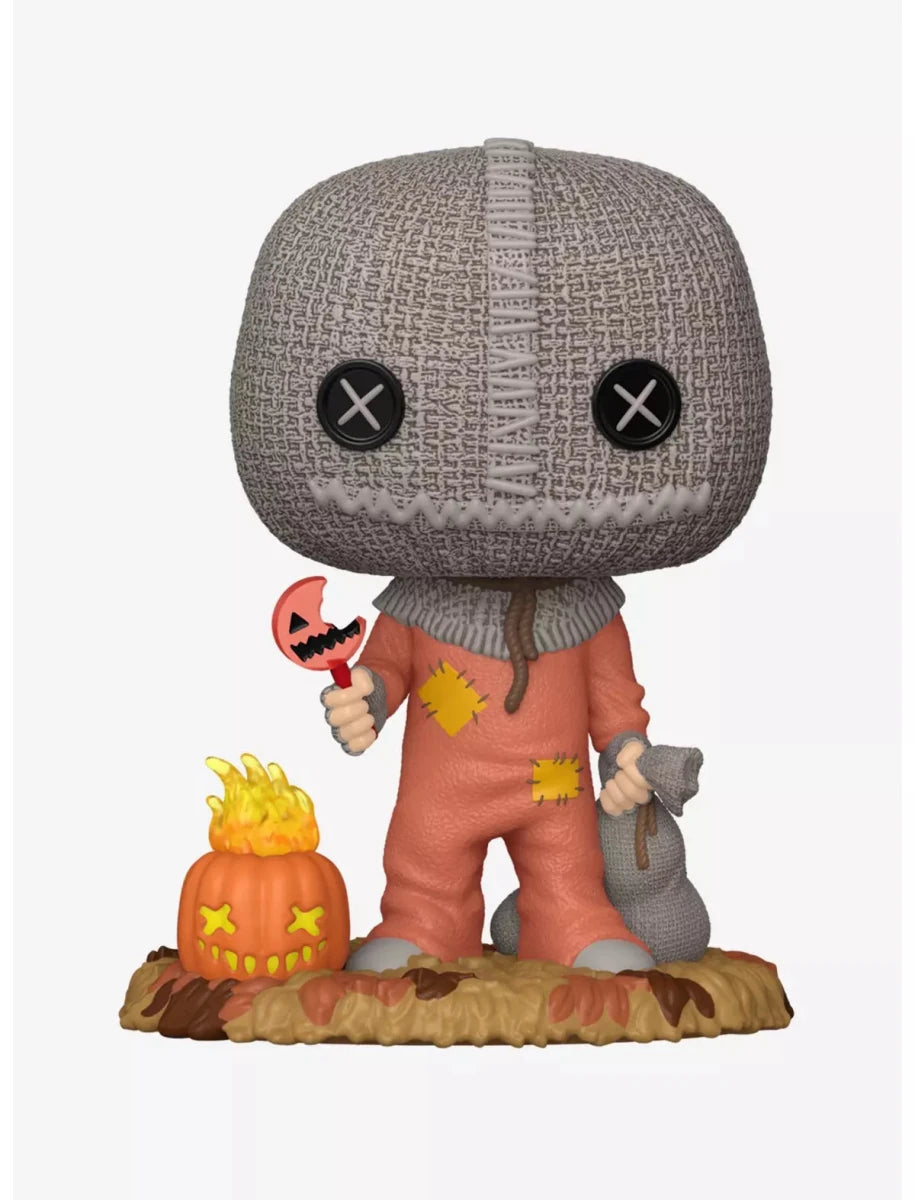 Funko Pop! vinyl figure of the character Leatherface from The Texas Chain Saw Massacre, featuring his signature gray knit mask, orange tattered suit, and accessories including a jack-o'-lantern and a cellophory bag, set against a plain white background.