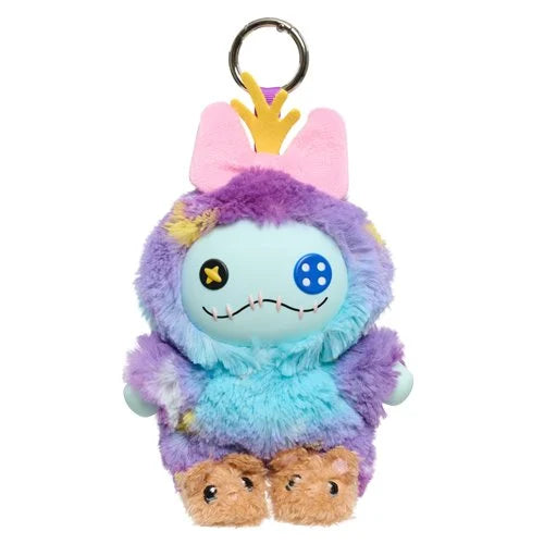 A plush monster keychain with fuzzy purple and light blue body, pink bunny ears, a small yellow crown, and brown feet, attached to a silver metal key ring on a plain white background.