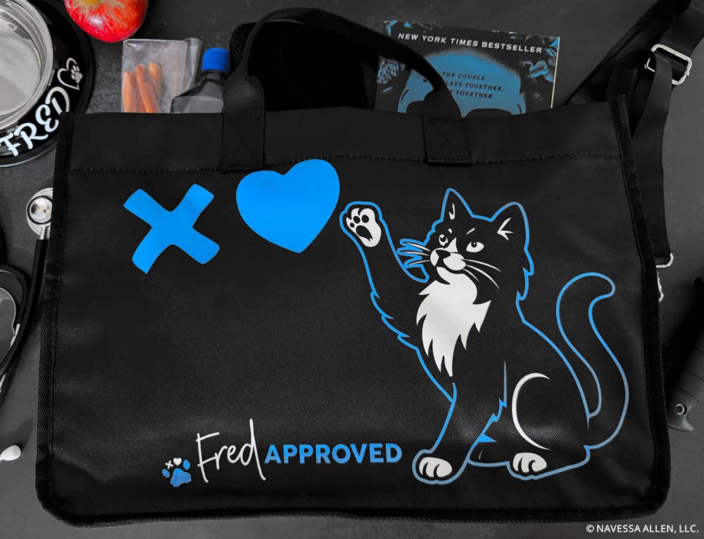 Black bag with a cat design and 'Fred Approved' text on a table.