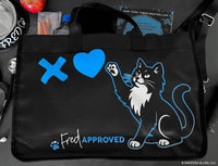 Black bag with a cat design and 'Fred Approved' text on a table.