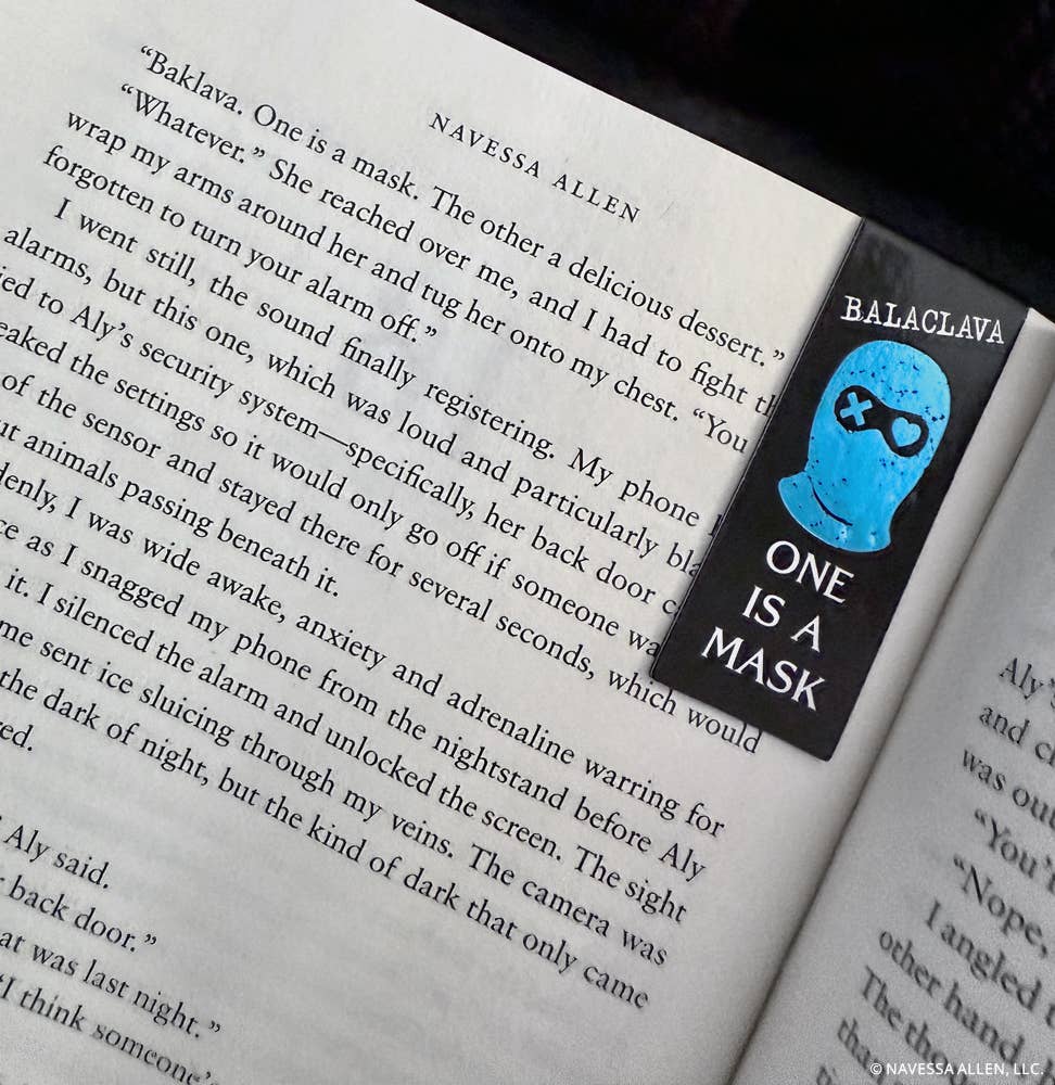 Book with a bookmark featuring a blue mask and text 'One is a Mask' on an open book.