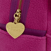 Close-up of a gold heart-shaped tag with 'Barney' branding on a purple textured surface.