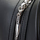 Close-up of a black leather bag with a silver knife-shaped zipper pull.