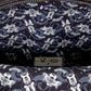 Close-up of a patterned fabric interior with repeating cartoon mouse faces in white and light blue on a dark navy background, plus a small black rectangular hardware piece and zipper visible at the top.