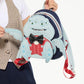 A person holds a small Disney Monsters backpack featuring the character Grommet. The backpack is light blue with a red polka-dot shirt, black bow tie, and dark blue straps, shown against a plain white background.