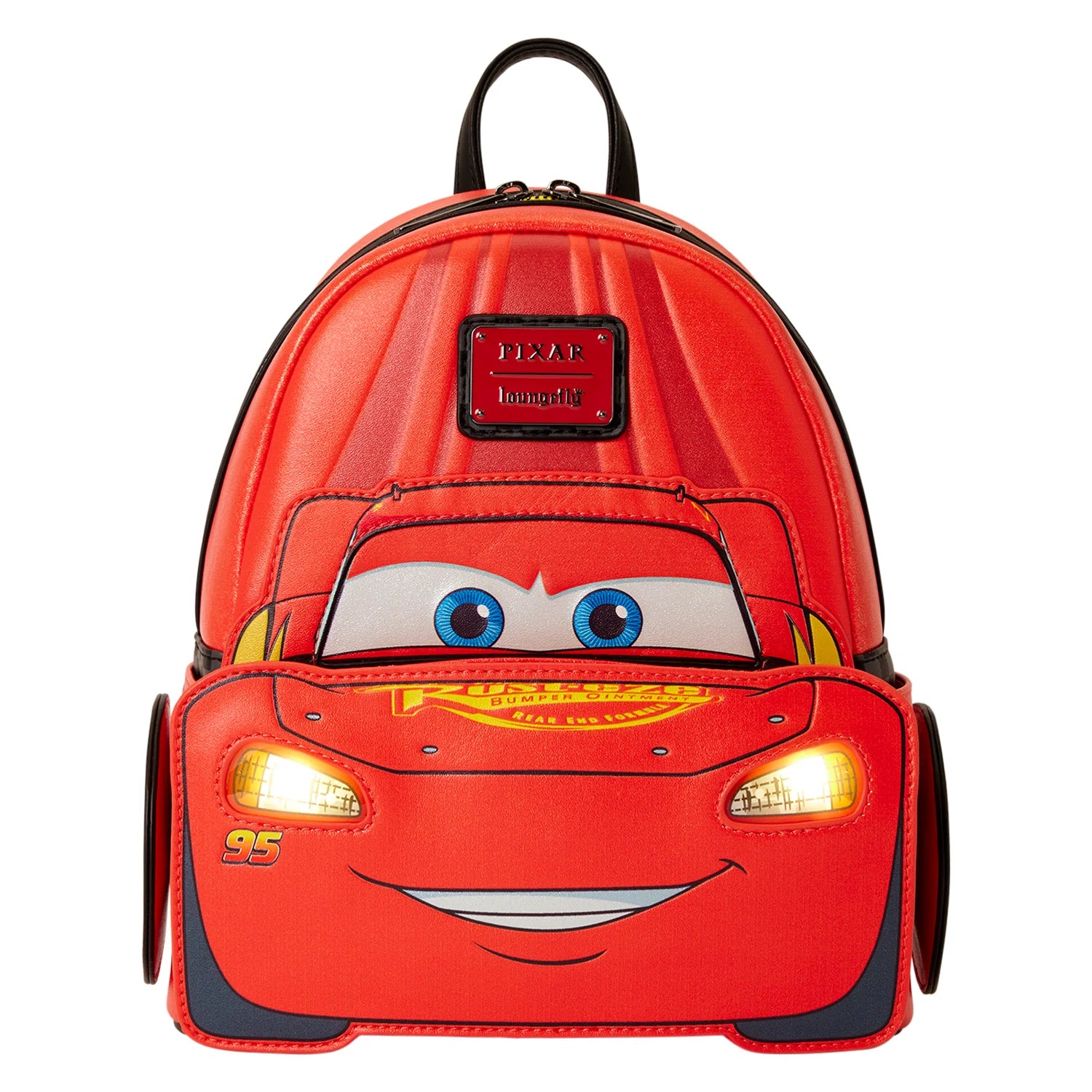 A red Disney Pixar Lightning McQueen backpack shaped like the character's car face, with blue eyes, a smiling mouth, and glowing yellow headlights, shown on a plain white background.