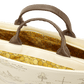 Close-up of a beige bag with brown handles and a detailed interior pattern.