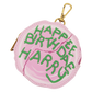 A round pink faux leather coin purse with a gold clasp, featuring green embroidered text that reads 'HAPPY BIRTH DAY HARRY' on a white background.