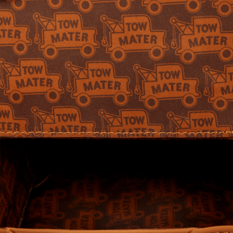 Close-up of a fabric surface with a repeating orange tow truck pattern and the words 'TOW MATE' on a dark brown background, with a stitched edge visible and a dark interior opening below.