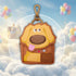 Keychain shaped like a cartoon dog with balloons and clouds in the background