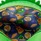 Close-up of the inside of a green zipper pouch, showing a blue fabric lining printed with a playful pattern of green frogs, yellow guitars, and assorted pies and cookies.