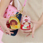 Two character-themed keychains held by a person against a checkered background