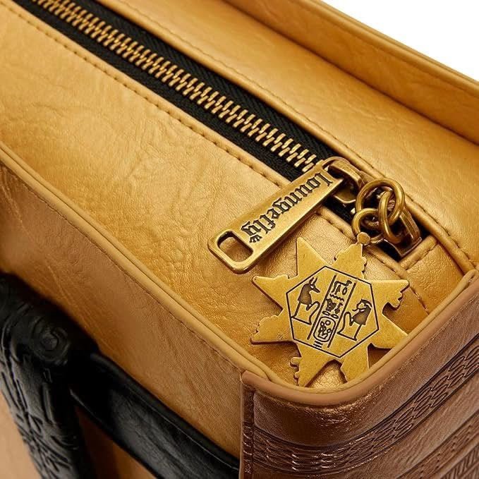 Close-up of a tan leather bag with a gold zipper pull featuring a star design.