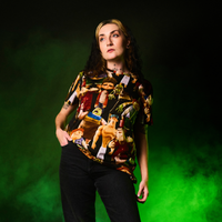 Person wearing a ParaNorman All Over Print T-Shirt with graphic designs against a green background