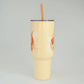 Yellow tumbler with a straw on a light gray background