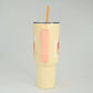 Yellow tumbler with a straw on a gray background