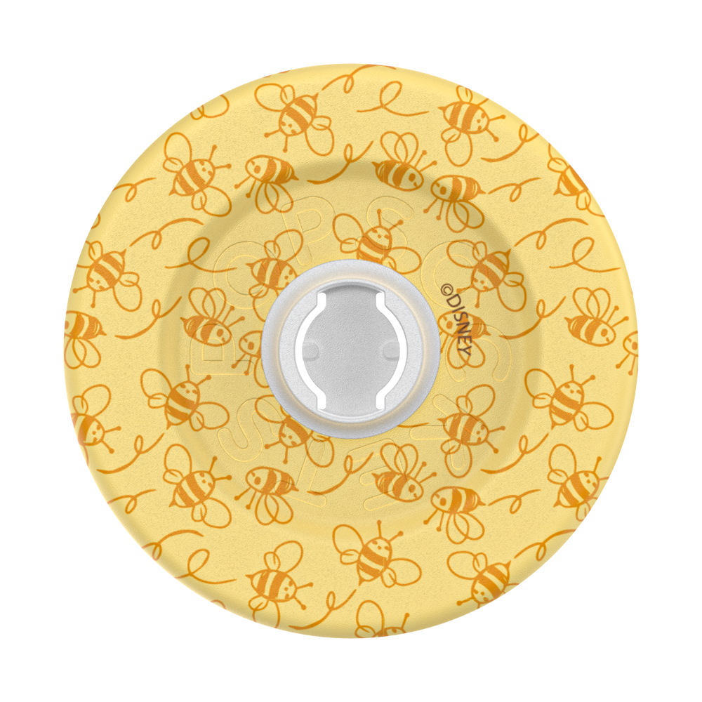 A round yellow silicone or rubber product, likely a bottle stopper or cap, featuring a repeating pattern of orange cartoon bees and swirls, with a white circular center.